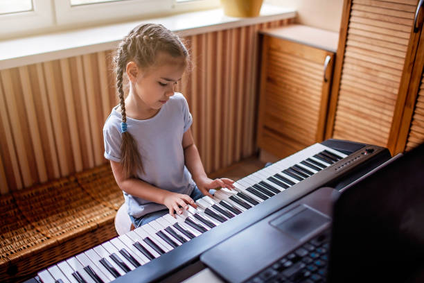自宅でのオンラインクラスで自宅で古典的なデジタルピアノを演奏する若いミュージシャン、自己孤立 - music child pianist learning ストックフォトと画像