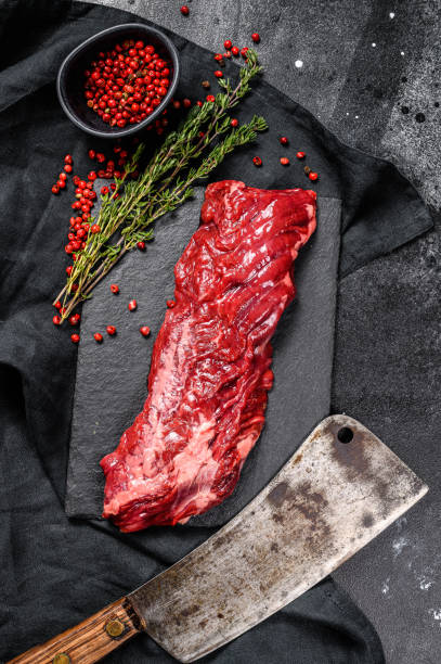 istock Raw marbled beef steak with pink pepper and thyme. Black background. Top view 1214119390