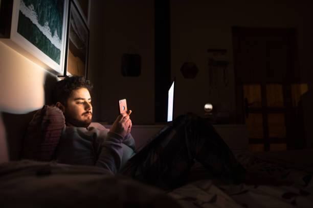 istock Connected at night - Young man with smartphone and laptop 1214120769