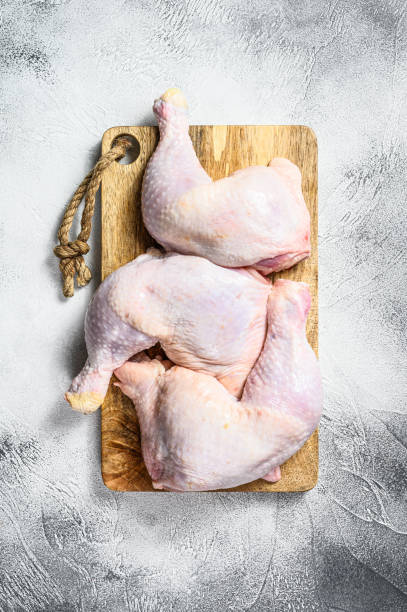 istock Raw chicken thighs on a chopping Board. Gray background. Top view 1214123731