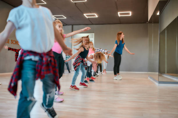 Learning modern dance. Happy boys and girls dancing with female dance teacher in the dance studio Learning modern dance. Happy boys and girls dancing with female dance teacher in the dance studio. Choreography concept. Sport. Active lifestyle dance studio instructor stock pictures, royalty-free photos & images