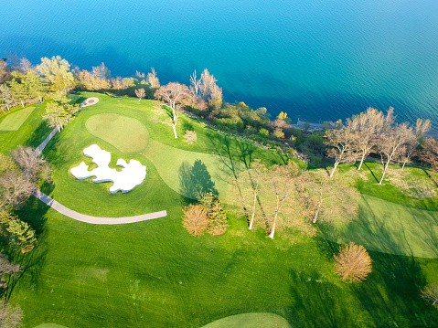Aerial view of the golf course with blue water lake. Empty golf course top view. Aerial view of golf field with green grass. Spring, summer fresh renew life concept.