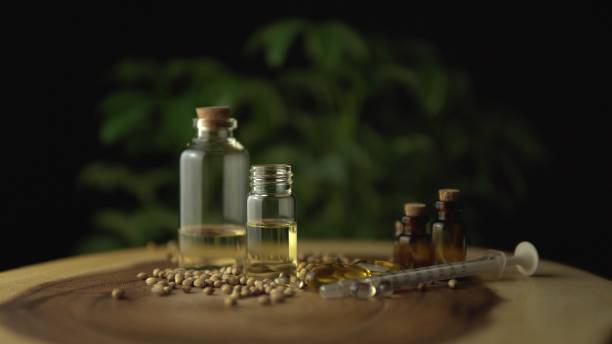 very close view of cbd oil, oral syringe, pills for anxiety and stress relief near the glass jar on the wood circle tree ring table with ripple line pattern. revolution in pain treatment and healing. - equimpent imagens e fotografias de stock