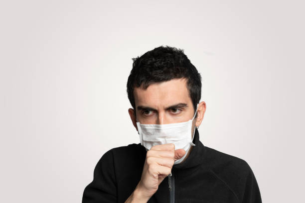 istock Young man sick with corona virus and coughing while hands covering mouth 1214128737