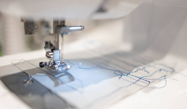 istock Close up view of sewing process. The stitching white fabric on professional manufacturing machine at workplace. 1214129737