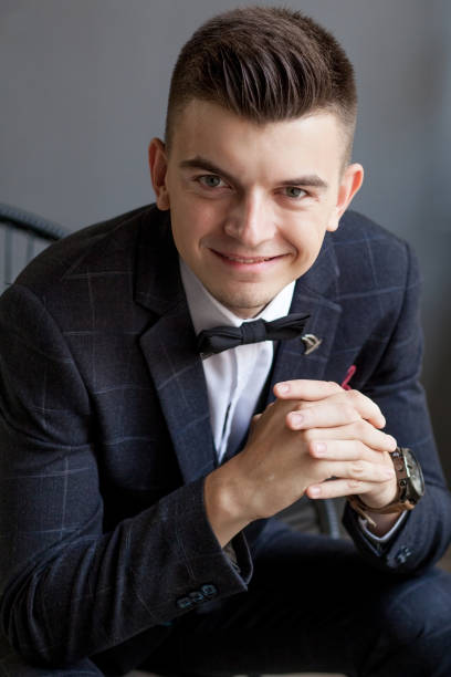 istock Concerned groom playing with his hands and looking to the side while wearing tuxedo, sitting on black studio background 1214130104