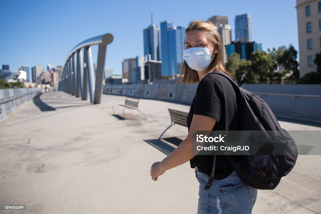 Woman Wearing Face Mask Walking to Melbourne City Waist up shot of a young woman wearing a face mask. She is walking to Melbourne city. Melbourne - Australia Stock Photo
