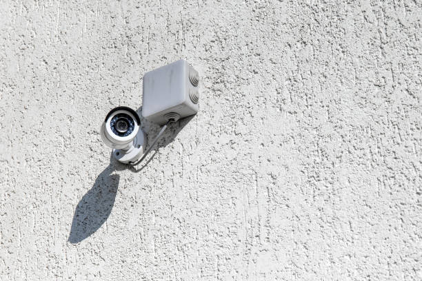 istock outdoor surveillance camera on a light wall, copy space 1214135943