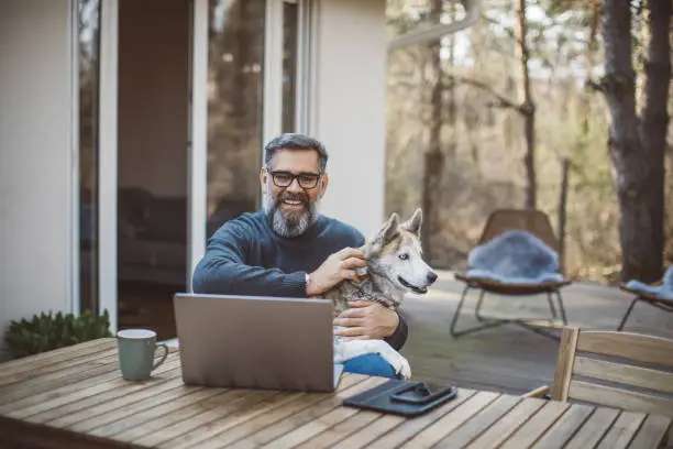 Mature men at home during pandemic isolation. His dog is with him