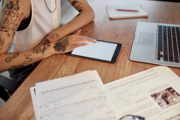 istock New software. Young tattooed woman with short haircut using digital tablet while sitting at her workplace. Business woman at work 1214137457