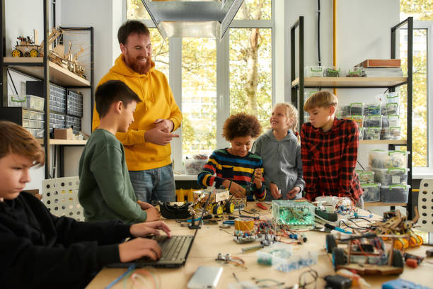 istock People Making Technology Work. Young technicians building a robot vehicle together with a male teacher at a stem robotics class. Inventions and creativity for kids 1214140162