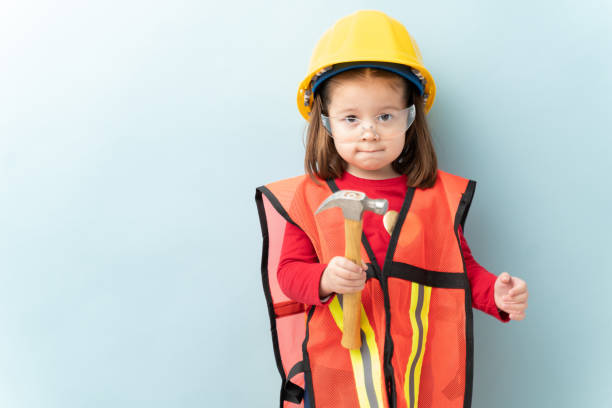 Little aspiring construction worker Beautiful little girl aspiring to work in construction and wearing a helmet and a vest and using a hammer career girl stock pictures, royalty-free photos & images