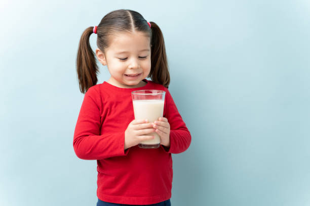 little girl drinking a glass of milk - milk child drinking little girls imagens e fotografias de stock
