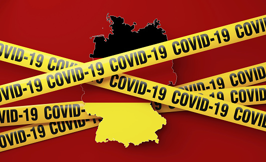Germany map surrounded by COVID-19 imprinted tape barriers on red background. Horizontal composition with copy space. COVID-19 quarantine and pandemic concept.