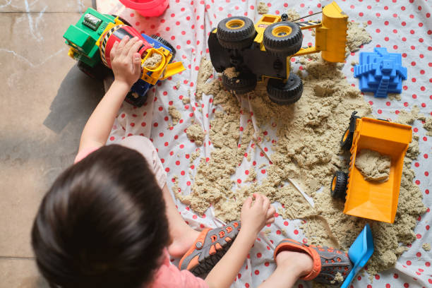 bird eye view of toddler boy playing with kinetic sand at home, child playing with toy construction machinery, creative play for kids concept - sandbox child human hand sand imagens e fotografias de stock