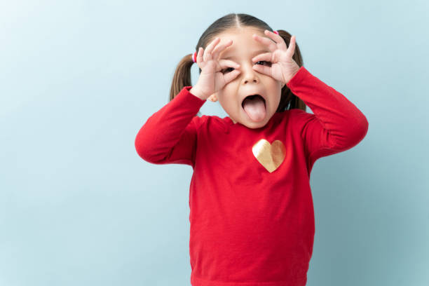 Little girl making funny faces Cute little girl making funny faces with her hands and tongue out in a studio making a face stock pictures, royalty-free photos & images