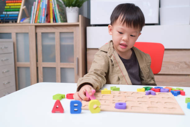 nette lächelnde kindergarten junge spielen mit alphabet blöcke, asiatische kinder lernen englisch mit holz pädagogische abc spielzeug puzzle - english game stock-fotos und bilder