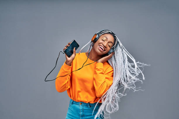 hermosa mujer escuchando música con sus auriculares y bailando. - vibrant color yellow recreational equipment red fotografías e imágenes de stock