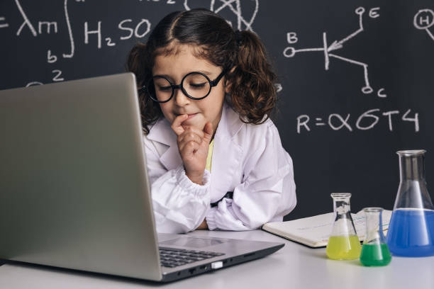 petite fille de scientifique regardant à l’ordinateur - blackboard child thinking little girls photos et images de collection