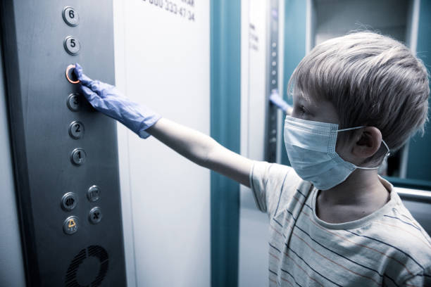 Boy uses medical gloves pressing the lift button stock photo