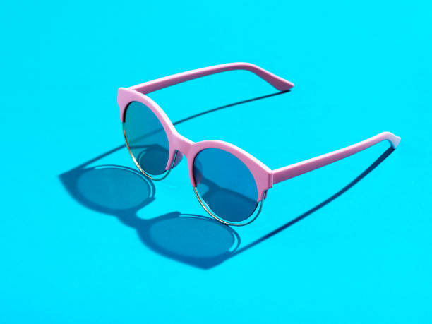 Trendy minimal style photography of  pink sunglasses on pastel blue background. Minimalist summer fashion or vacation concept. Sunny and vivid background with hard light and shadow.