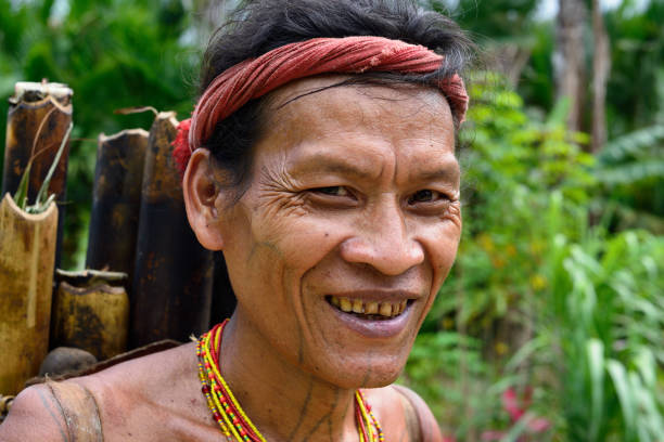 Muara Siberut, Mentawai Islands, Indonesia, 5 NOVEMBER 2019: Portrait  tribal men with traditional tattoos coming back from the jungle. He is carrying the basket on his back with bamboo, inside with the meat of a wild pig