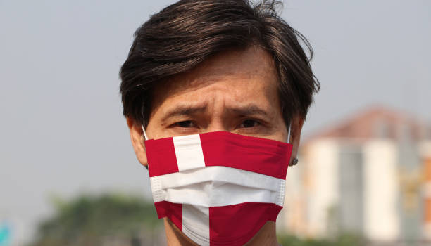 Denmark flag on hygienic mask. Masked the man prevent germs. stock photo