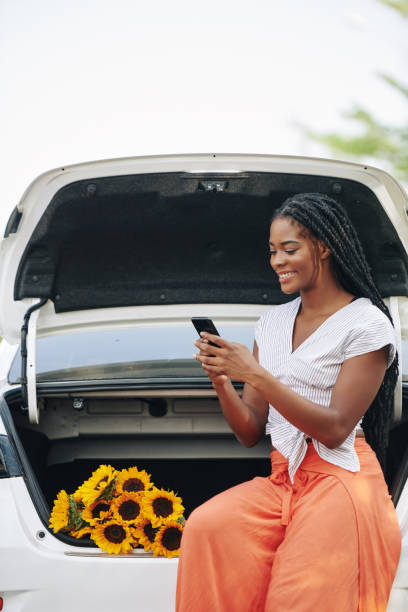 istock Texting woman sitting in car trunk 1214165955