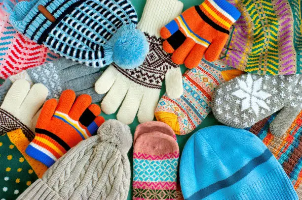 Warm clothes in the form of knitted hats, mittens, gloves, scarves for the cold seasons. Multi-colored clothes for autumn and winter.