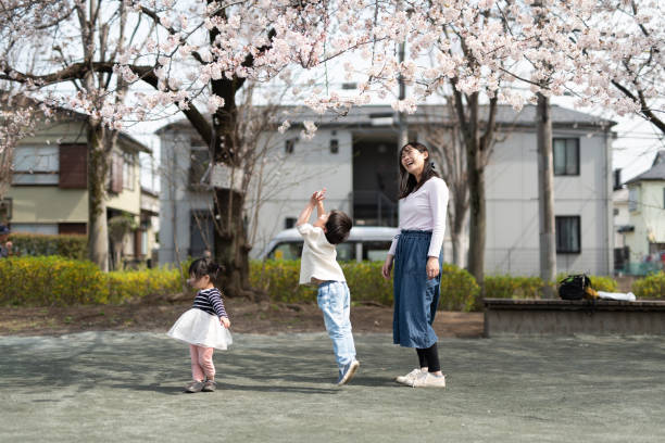 madre e hijos jugando frente a los cerezos - child dancing preschooler outdoors fotografías e imágenes de stock