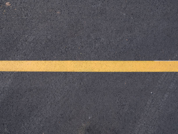 istock Yellow line across dark asphalt 1214172258