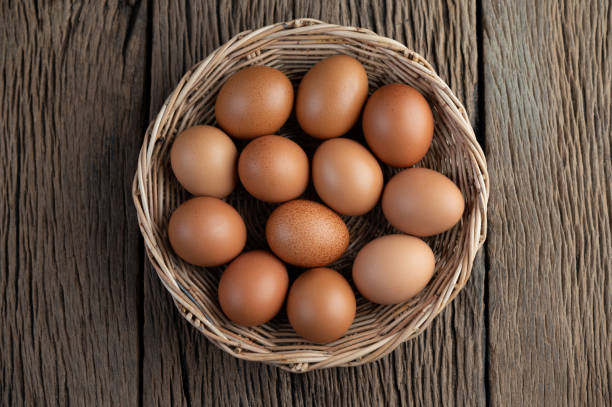 Lay eggs in a wooden basket on a wooden floor. Top view. stock photo