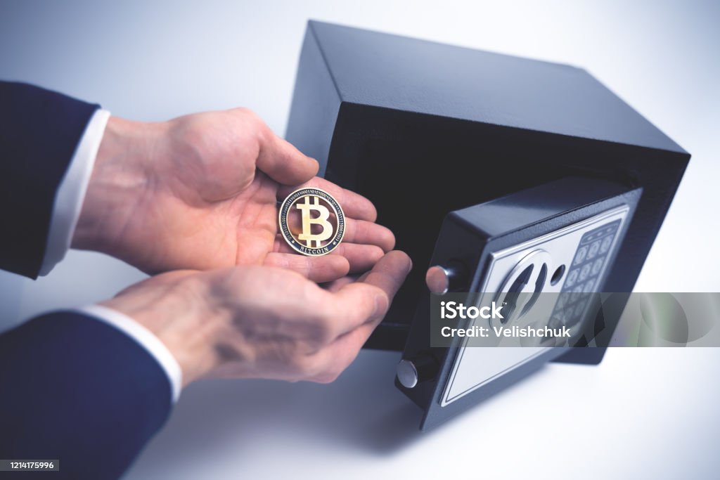 Safe Deposit. Symbol of cryptocurrency safety. The man puts a physical bitcoin in small Residential Vault. Toned soft focus picture Safe Deposit. Symbol of cryptocurrency safety. The man puts a physical bitcoin in small Residential Vault. Toned soft focus picture. Bitcoin Stock Photo