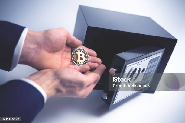 Safe Deposit Symbol Of Cryptocurrency Safety The Man Puts A Physical Bitcoin In Small Residential Vault Toned Soft Focus Picture Stock Photo - Download Image Now