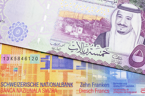 Una nota de franco suizo con una nota riyal de Arabia Saudita photo