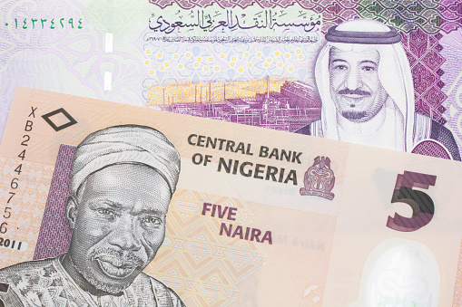 Una factura de naira nigeriana con un billete de cinco riales sauditas de cerca photo