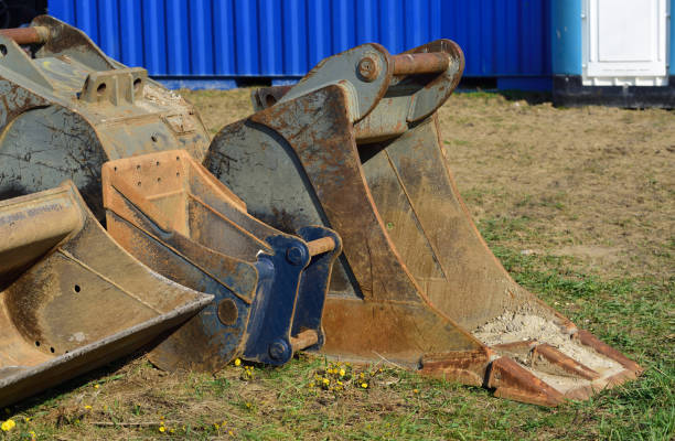 Several used and dirty excavator shovels lie on an abandoned construction site on Earth