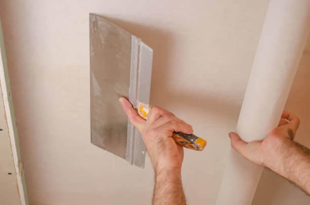 istock The Builder puts plaster on the wall.Hand holding a spatula with construction mix and smoothes out bumps.Repair the wall.Plaster the wall with a putty knife. 1214188902