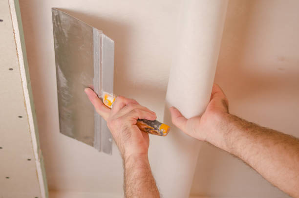 istock The Builder puts plaster on the wall.Hand holding a spatula with construction mix and smoothes out bumps.Repair the wall.Plaster the wall with a putty knife. 1214189653