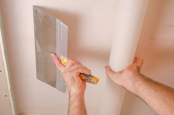 istock The Builder puts plaster on the wall.Hand holding a spatula with construction mix and smoothes out bumps.Repair the wall.Plaster the wall with a putty knife. 1214189724