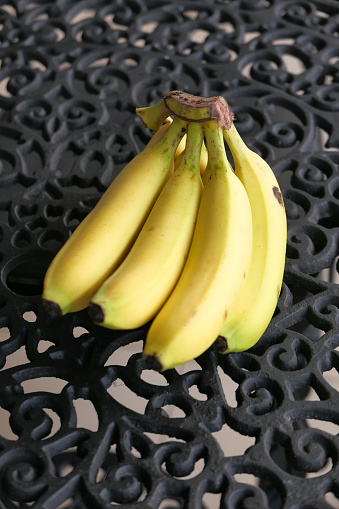 High angle view of bananas in a white plastic bowl over a rustic wood table in the kitchen