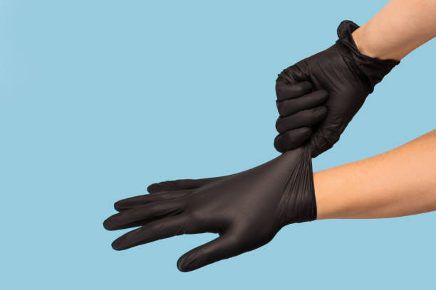 istock man puts on sterile black gloves on a blue background. Hazard, hygiene 1214193566