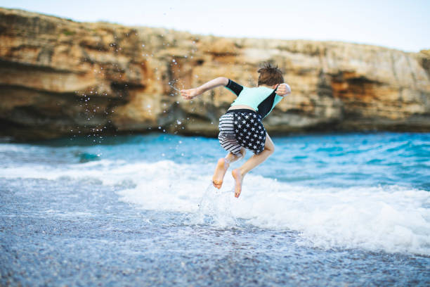 istock Little boy playing and splashing in sea 1214193671