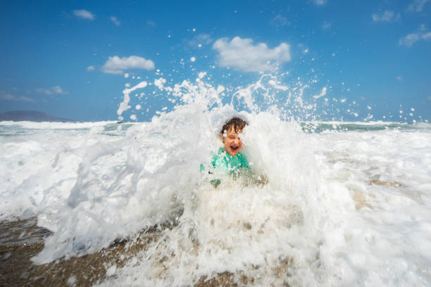 istock Little boy playing and splashing in sea 1214193764