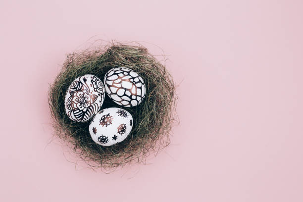 Three easter eggs are painted in black and white lie in a green nest