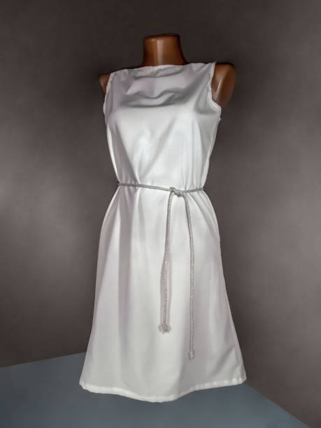 istock Simple white dress with a belt on a mannequin, isolated on a dark background 1214197123