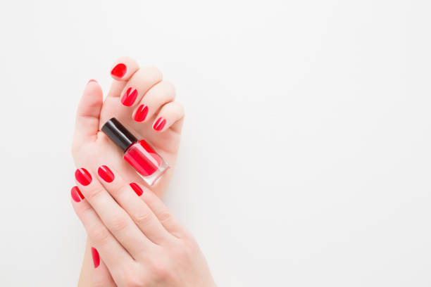 Beautiful groomed woman fingers with red nails on white table background. Young girl hand holding bottle of nail polish. Closeup. Manicure, pedicure beauty salon concept. Empty place for text or logo. Beautiful groomed woman fingers with red nails on white table background. Young girl hand holding bottle of nail polish. Closeup. Manicure, pedicure beauty salon concept. Empty place for text or logo. red nail polish stock pictures, royalty-free photos & images