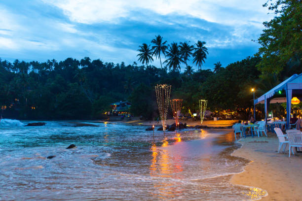 istock Oceanfront restaurant with lights and tables on a sandy beach 1214201131