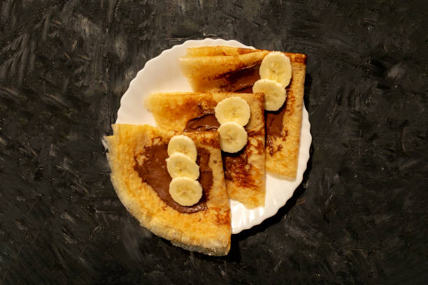 Fresh pancakes with chocolate paste and banana on gray background. Russian style pancakes for Pancake Week. English breakfast