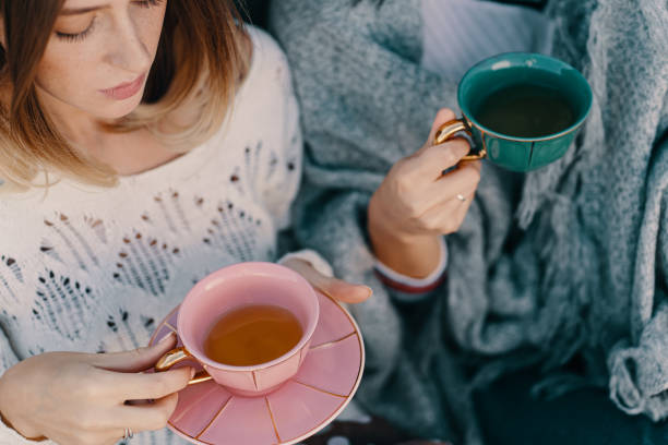 Two attractive girls enjoy a tea party. Drinking healthy buckwheat tea. Healthcare or herbal medicine concept. Close-up on mugs